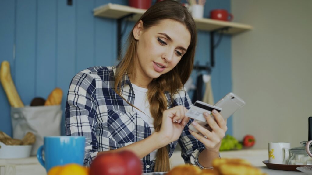 Woman checking her card details on her phone in the kitchen